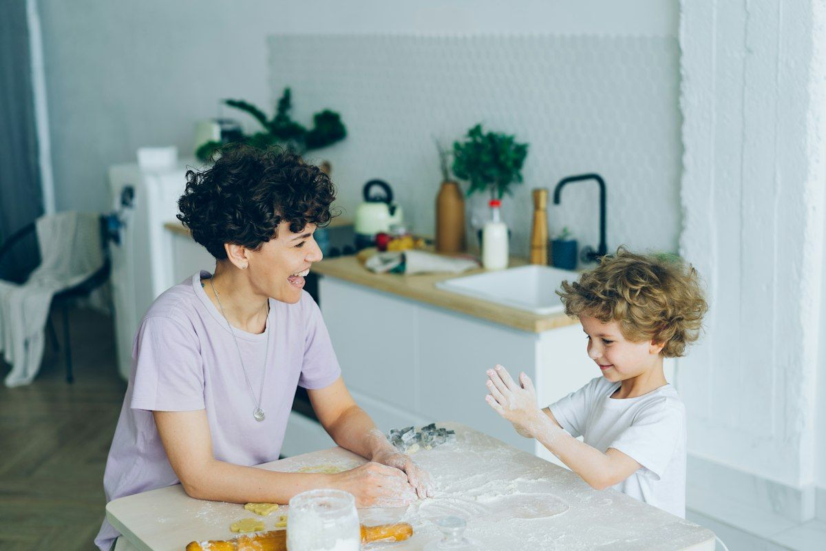 Smiling mom and young son baking together at the kitchen table